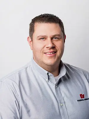 A man in a light blue shirt with a "Federal Industrial" logo smiles at the camera against a plain white background.