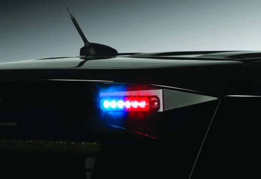 Close-up of police car roof with illuminated red and blue emergency lights.