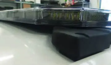 A blurred image of dark, rectangular objects stacked on a white surface in an indoor setting.