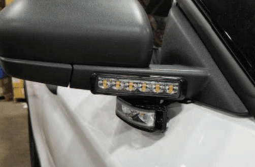 Close-up of a car side mirror with integrated LED turn signal lights and an additional smaller light underneath.
