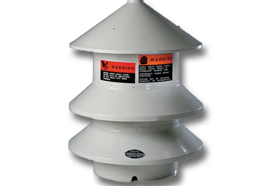 The FedSig Model 2 Omni-Directional Siren is a white, cylindrical outdoor warning siren featuring a conical top and multiple tiers, complete with warning labels.