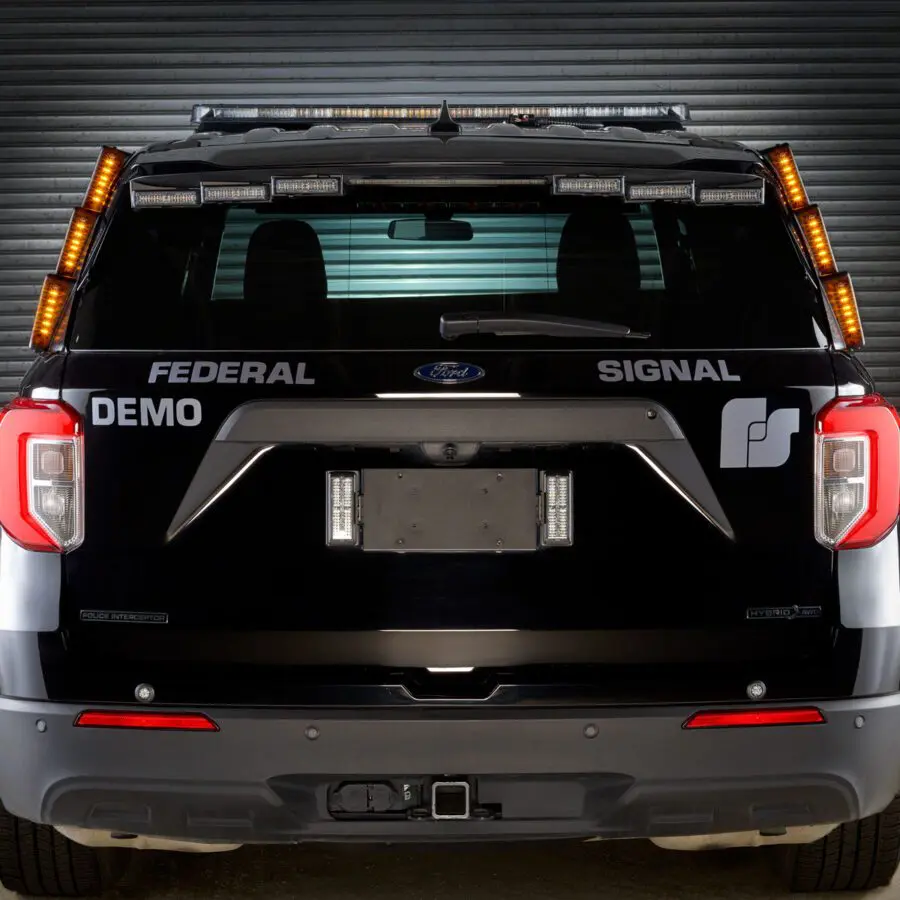 Rear view of a black vehicle with "Federal Signal" and "Demo" written on the back, equipped with amber emergency lights on top.