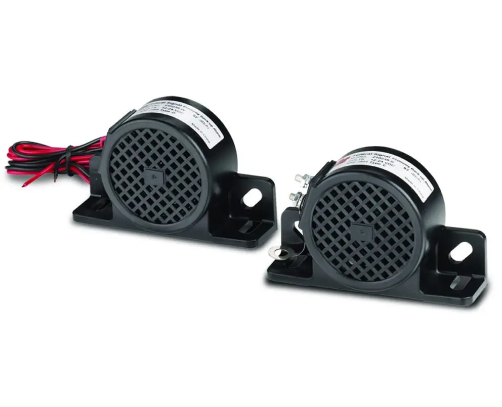 Two FedSig 2012 Series Alarms, featuring black grid-like front panels and mounted on rectangular bases, with visible wires extending from the sides.