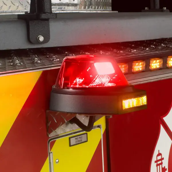 Close-up of a fire truck's red emergency light and reflective striping, with a small compartment labeled "Pike Pole Storage.
