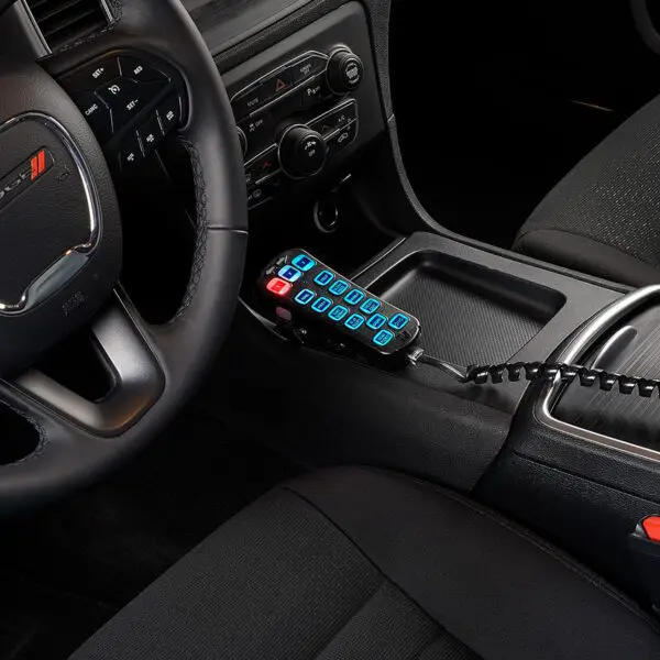 Car interior with a steering wheel, dashboard controls, and a custom keypad with illuminated blue buttons in the center console.