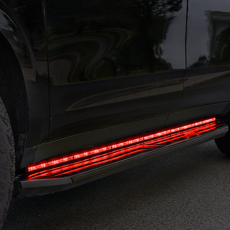 Close-up of a black vehicle parked on a road, featuring an illuminated red LED strip along the lower side panel.