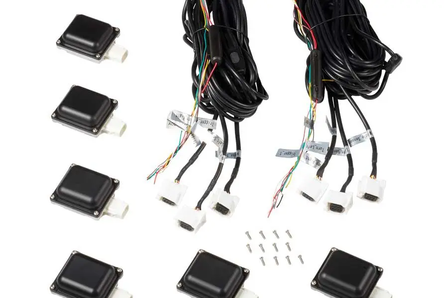 The Perimeter Breach Warning System includes six black rectangular sensors, two wiring harnesses with connectors, and a set of screws arranged on a white background.