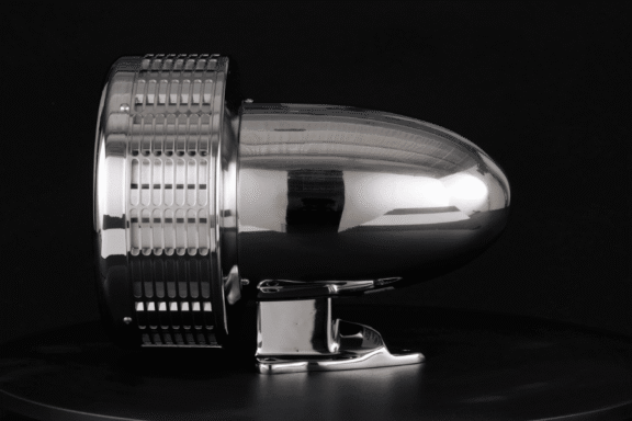 A metallic, bullet-shaped object with a vented cylindrical base is displayed against a black background.
