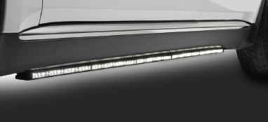 Illuminated running board beneath a vehicle door, with a visible light strip for ease of entry.